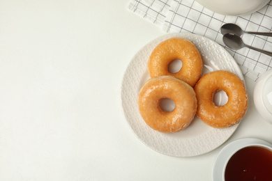 Photo of Delicious donuts on white table, flat lay. Space for text