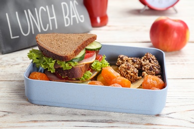 Lunch box with appetizing food on wooden table