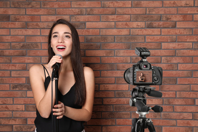 Image of Music teacher recording singing lesson near brick wall