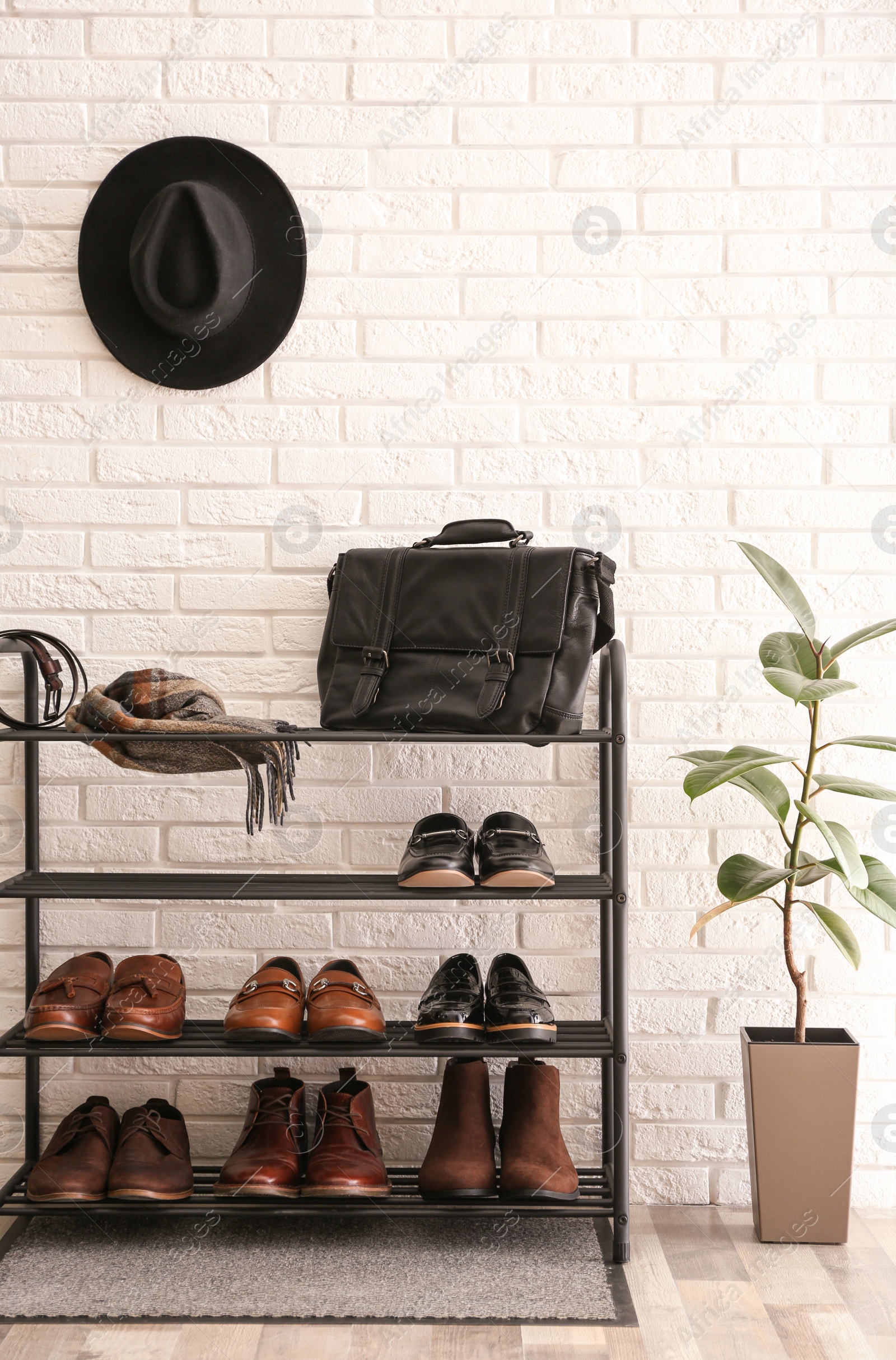 Photo of Shelving rack with stylish shoes and accessories near white brick wall indoors