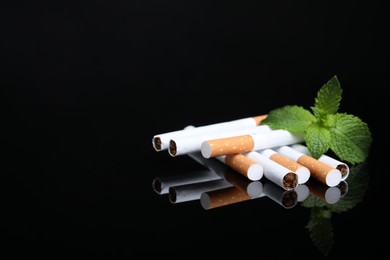 Photo of Menthol cigarettes and mint on black background, space for text