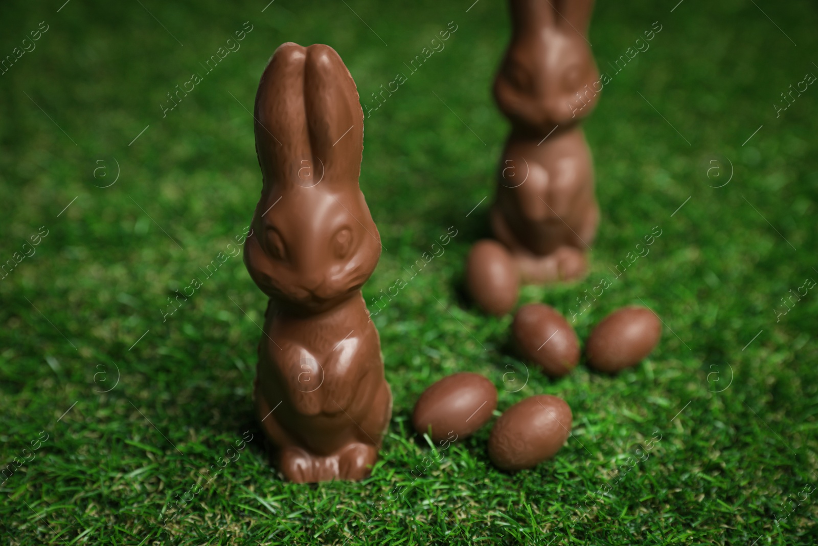 Photo of Chocolate bunnies and eggs on green grass. Easter celebration