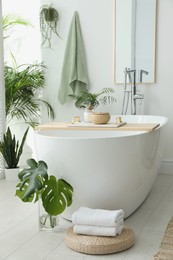 Photo of Stylish bathroom interior with modern tub, houseplants and beautiful decor. Home design