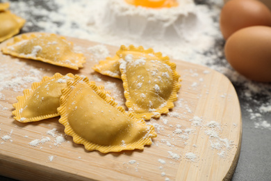 Photo of Raw ravioli on wooden board, closeup view. Italian pasta