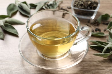 Cup of aromatic sage tea on wooden table