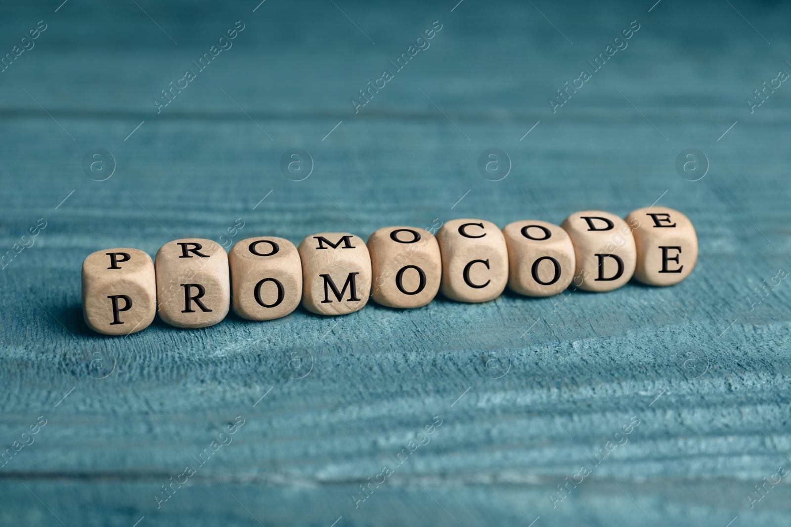 Photo of Wooden cubes with words Promo Code on blue table