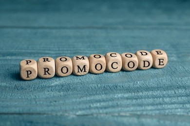 Photo of Wooden cubes with words Promo Code on blue table
