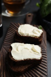 Photo of Bread with cream cheese on wooden board, closeup