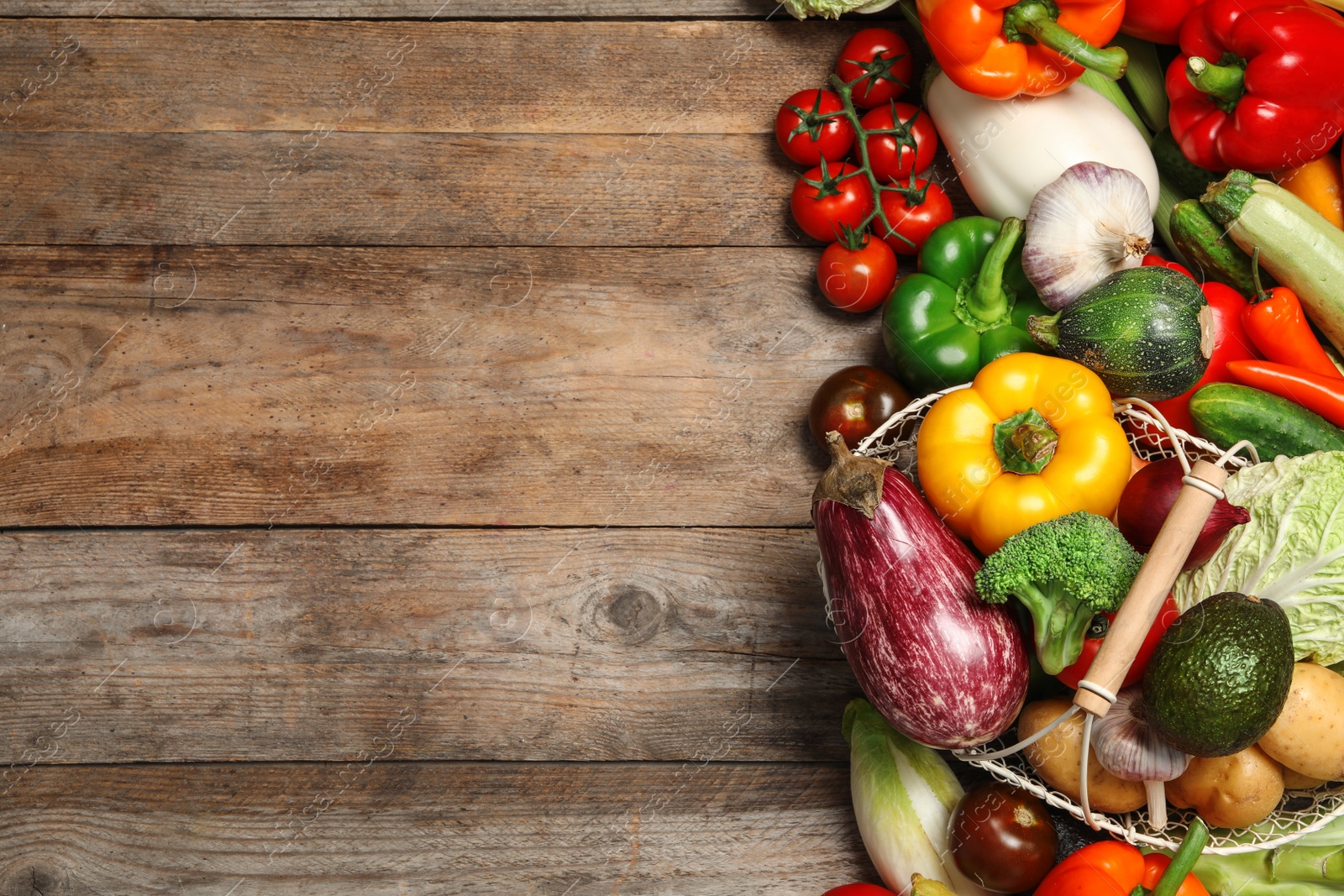 Photo of Fresh vegetables and metal basket on wooden table, flat lay. Space for text