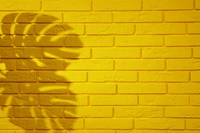 Photo of Shadow of monstera leaves on yellow brick wall, space for text