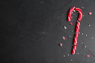 Photo of Crushed Christmas candy cane on black background, flat lay. Space for text