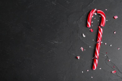 Crushed Christmas candy cane on black background, flat lay. Space for text