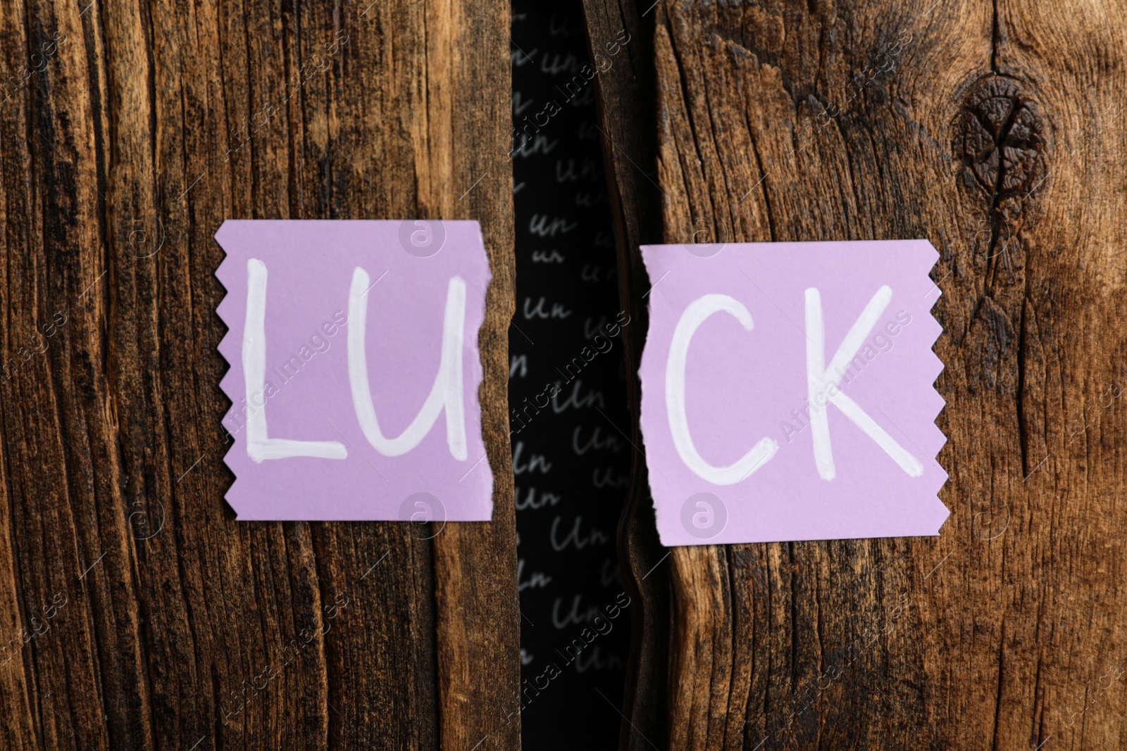 Photo of Torn card with word LUCK on wooden background