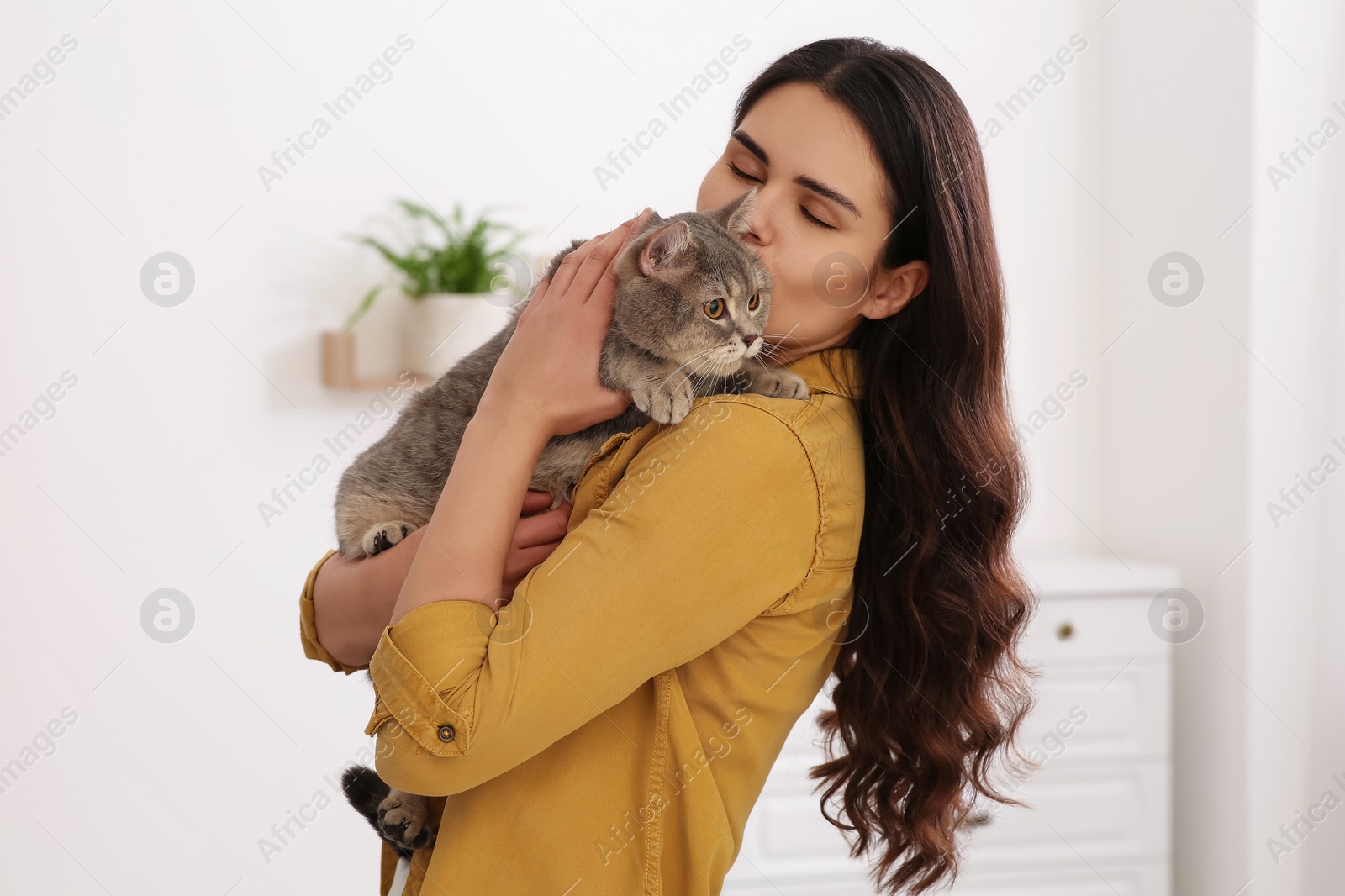 Photo of Young woman kissing her adorable cat at home