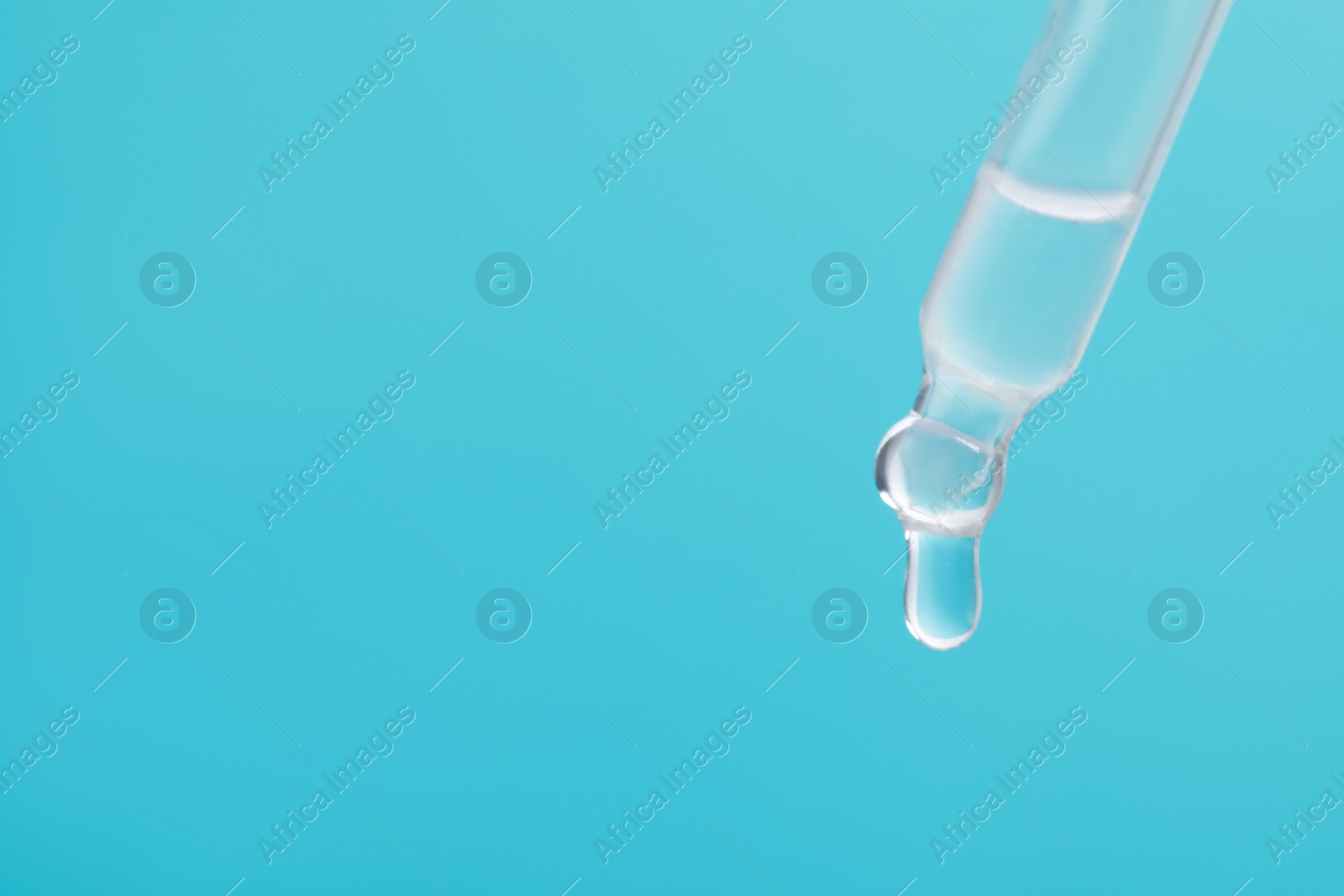 Photo of Dripping serum from pipette on light blue background, closeup. Space for text