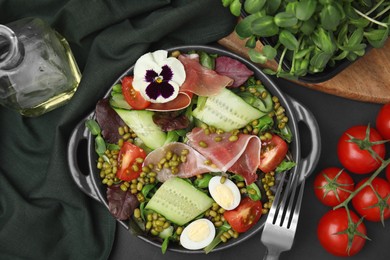 Photo of Bowl of salad with mung beans on black table, flat lay