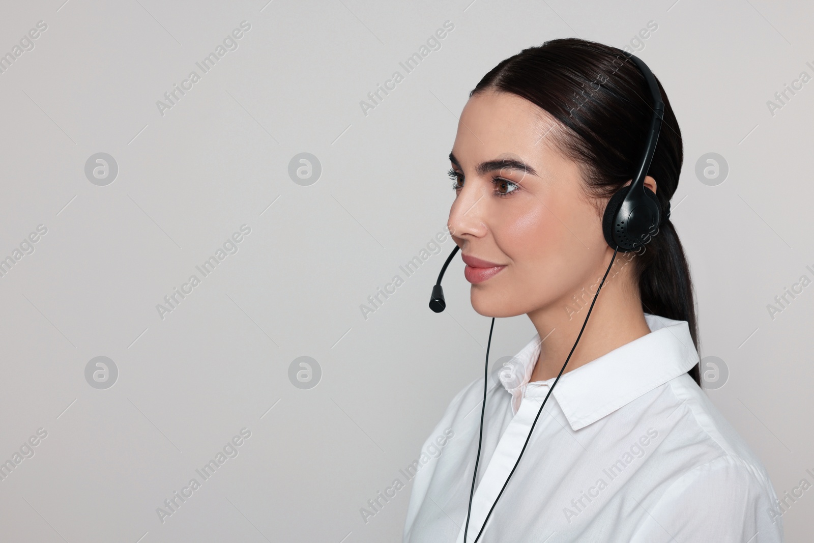 Photo of Hotline operator with modern headset on light grey background, space for text. Customer support