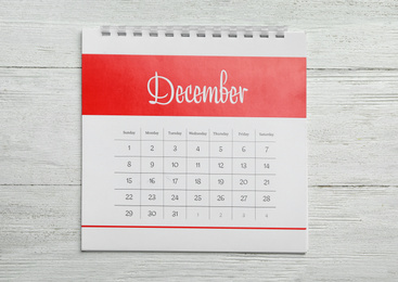 Photo of December calendar on white wooden background, top view