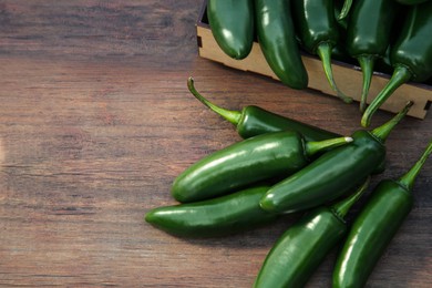 Photo of Green jalapeno peppers on wooden table. Space for text