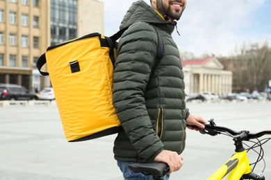 Courier with thermo bag and bicycle on city street, closeup. Food delivery service
