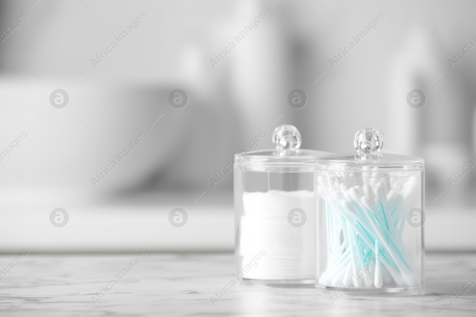 Photo of Plastic jars with cotton pads and swabs on white countertop in bathroom. Space for text