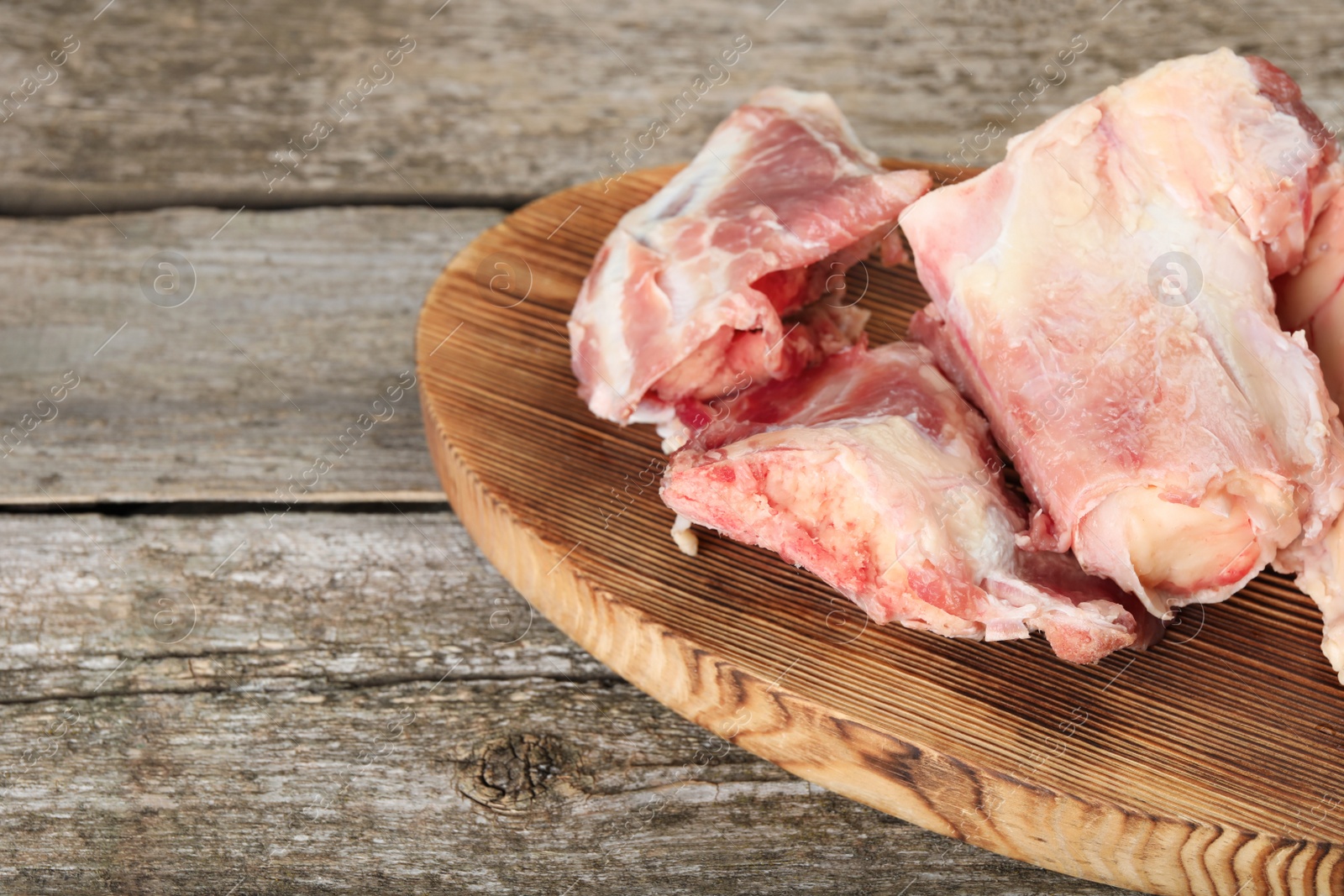 Photo of Cutting board with raw chopped meaty bones on wooden table. Space for text