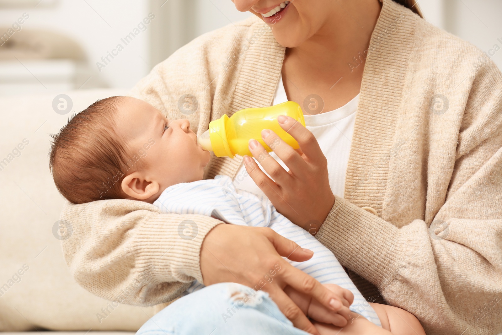 Photo of Mother feeding her cute child with infant formula indoors