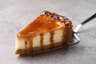 Pie server with piece of caramel cake on light table