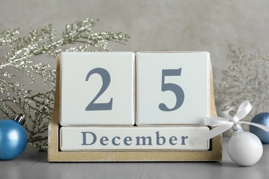 Photo of Wooden block calendar and Christmas decor on light grey stone table. Holiday celebration