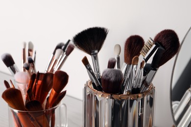 Set of professional brushes and mirror on table, closeup