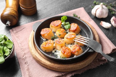 Photo of Delicious fried scallops in dish served on dark gray textured table, closeup