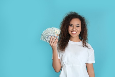 Young African-American woman with money on color background. Space for text