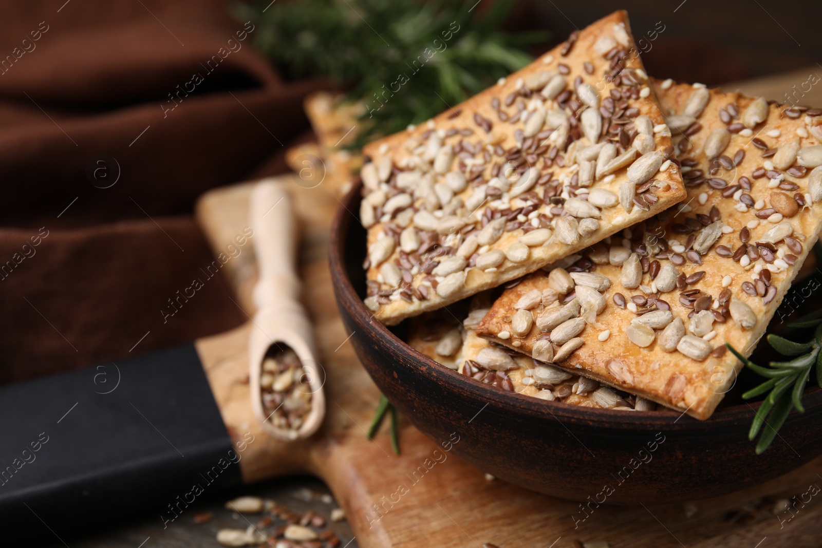 Photo of Cereal crackers with flax, sunflower, sesame seeds and rosemary on table, closeup. Space for text