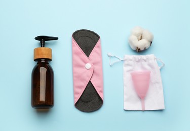 Photo of Flat lay composition with reusable cloth menstrual pad on light blue background. Female hygiene products