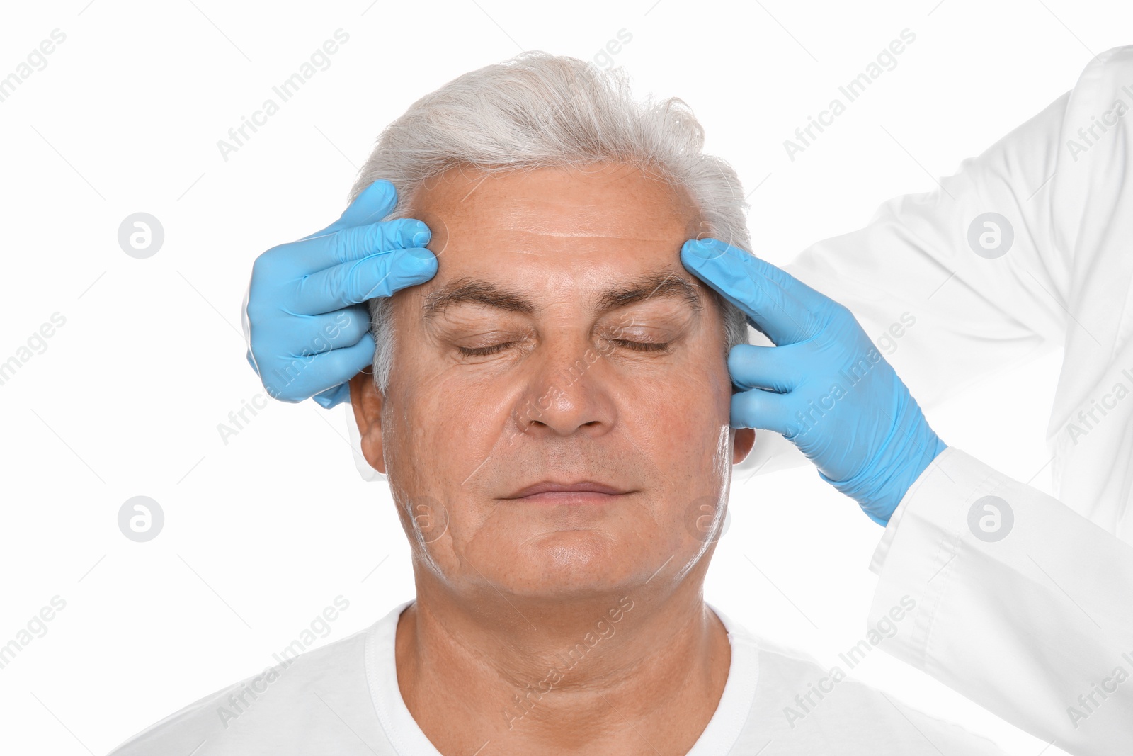 Photo of Doctor examining senior man face before cosmetic surgery on white background
