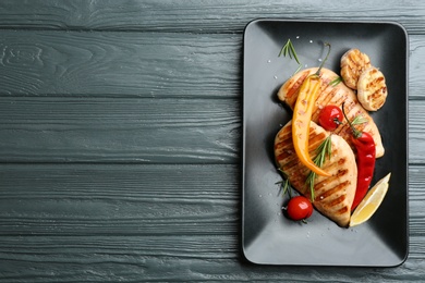 Tasty grilled chicken fillets with vegetables on grey wooden table, top view. Space for text