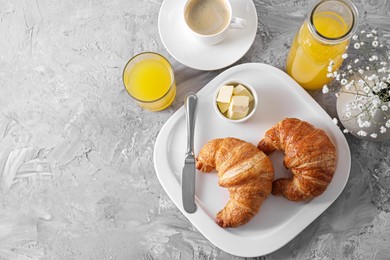 Photo of Tasty breakfast. Fresh croissants, coffee, juice and butter on grey table, flat lay. Space for text