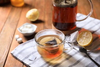 Photo of Tea bag in glass cup on wooden table