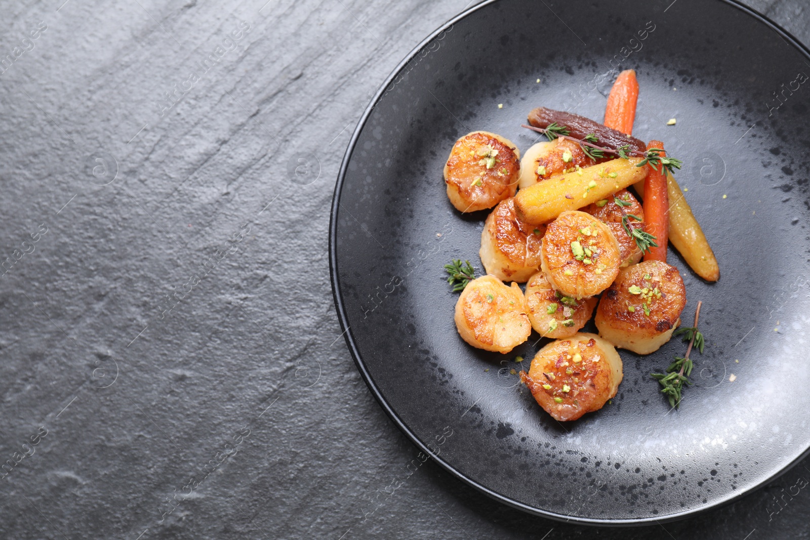 Photo of Delicious fried scallops on dark gray textured table, top view. Space for text