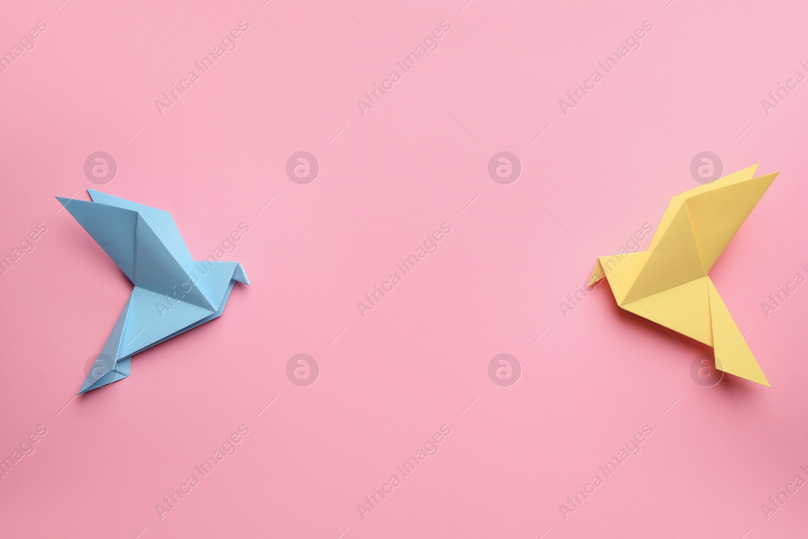 Photo of Beautiful colorful origami birds on pink background, flat lay. Space for text