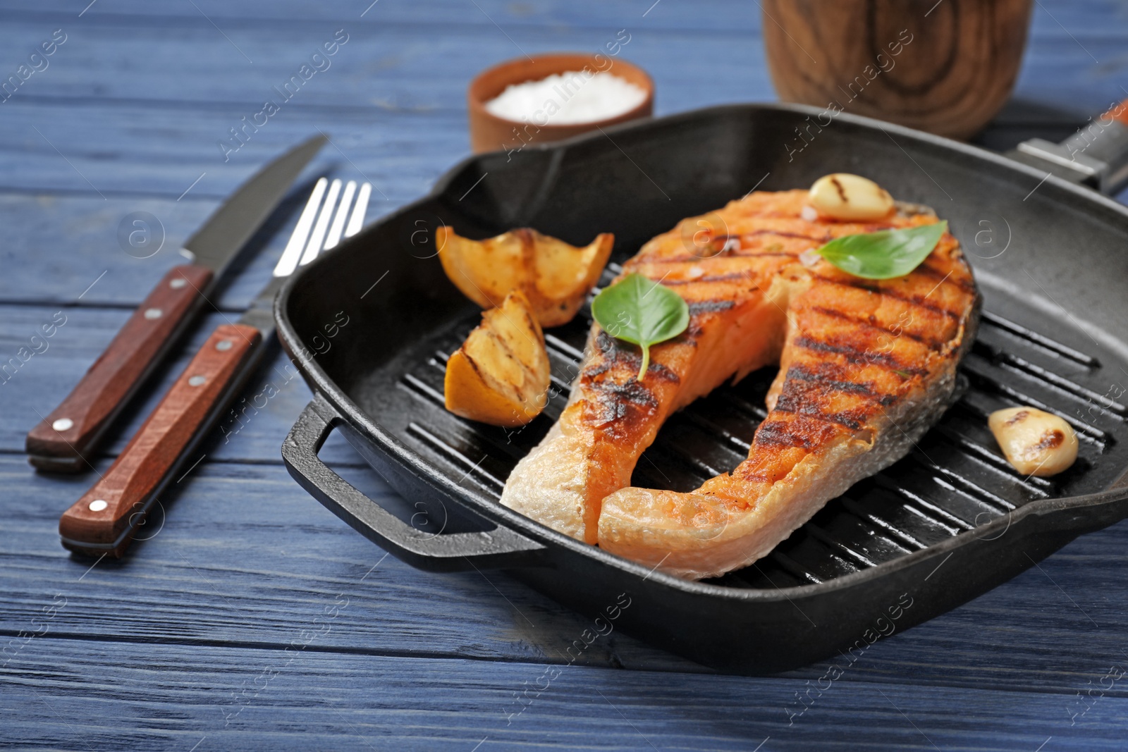 Photo of Frying pan with tasty salmon steak on wooden background