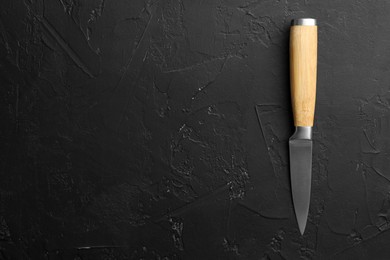 Photo of One sharp knife on dark textured table, top view. Space for text