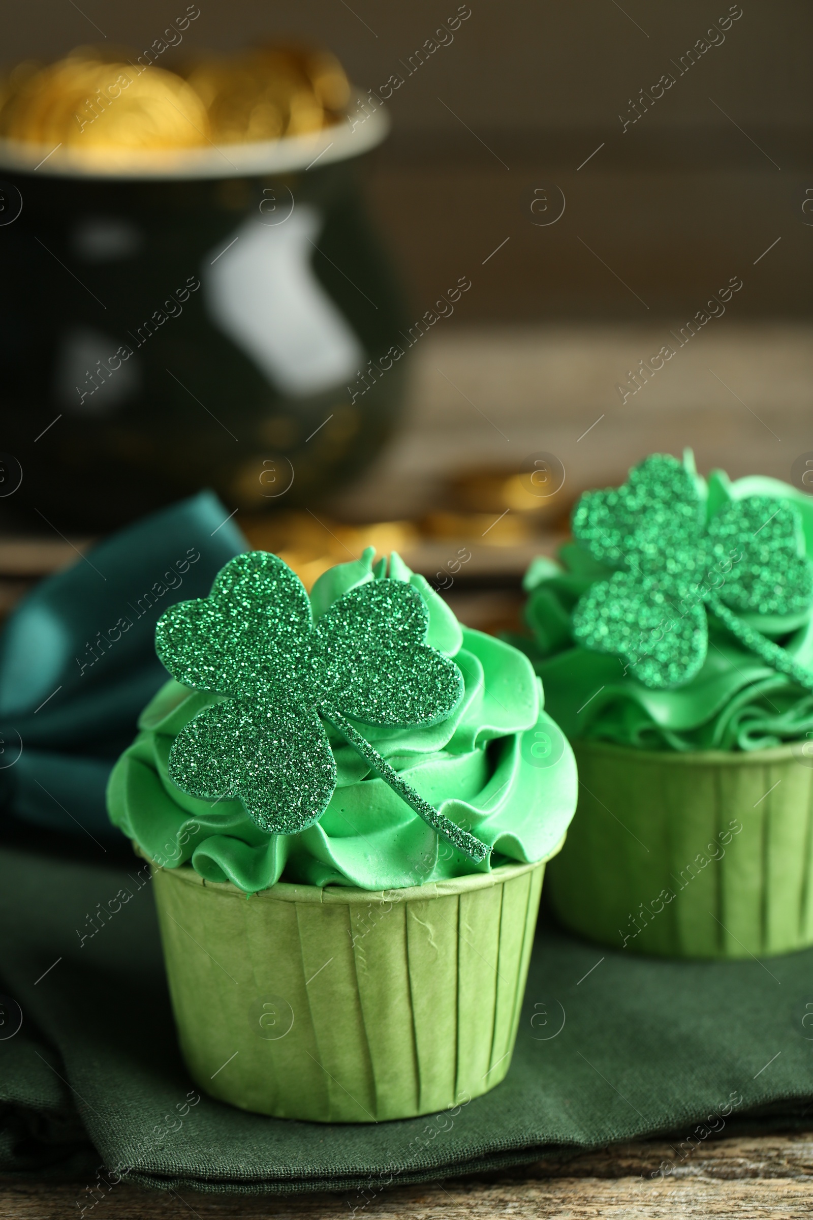 Photo of St. Patrick's day party. Tasty cupcakes with clover leaf toppers and green cream on wooden table, closeup