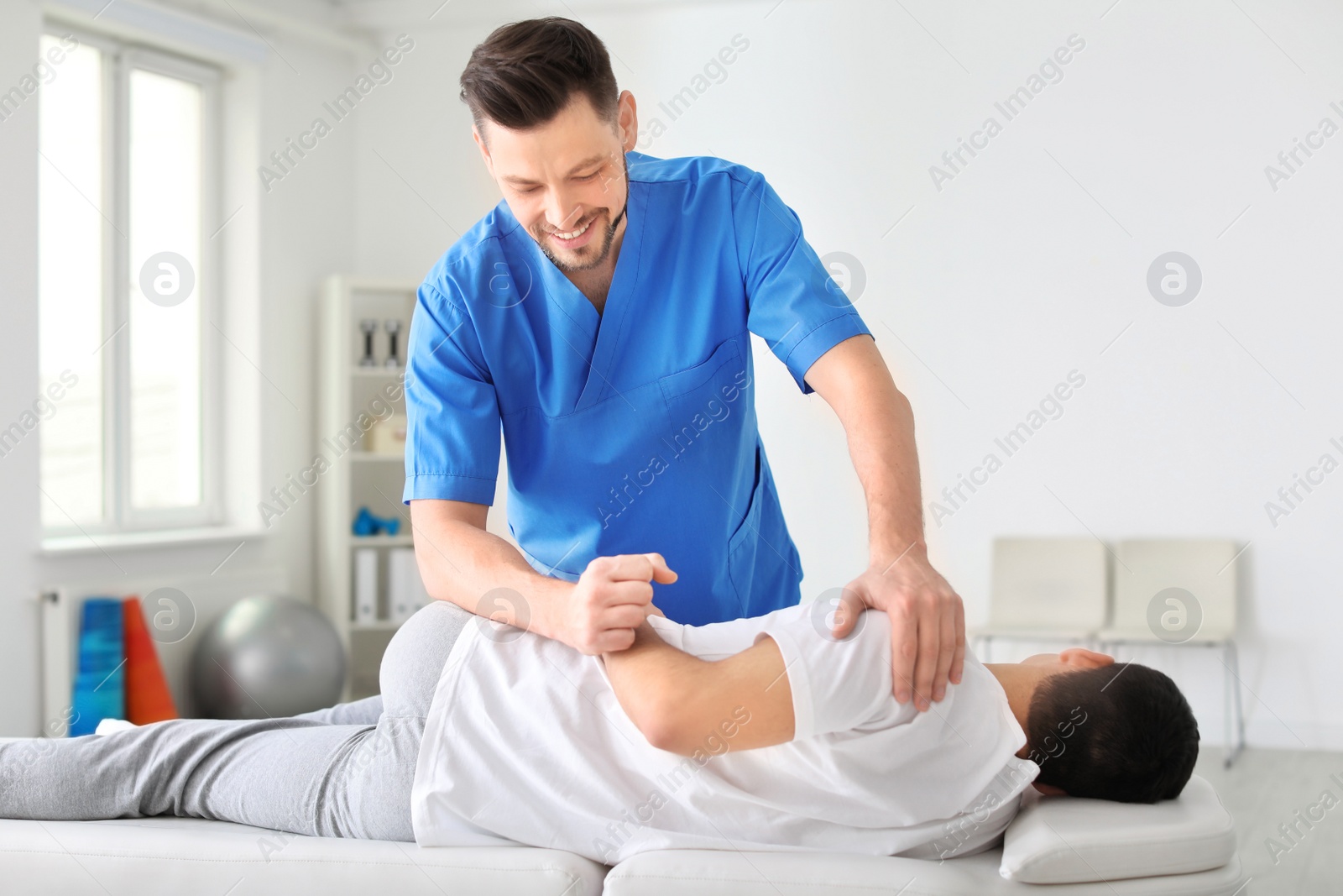 Photo of Physiotherapist working with male patient in clinic
