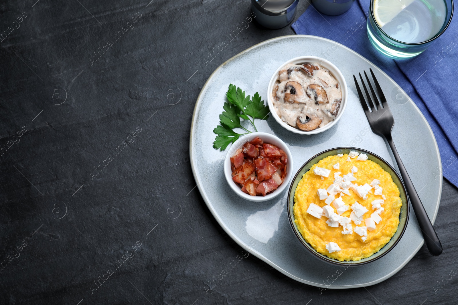 Photo of Traditional Ukrainian banosh served with brynza, pork cracklings and mushrooms on black table, flat lay. Space for text