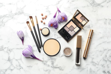 Photo of Many different makeup products and spring flowers on marble background, flat lay