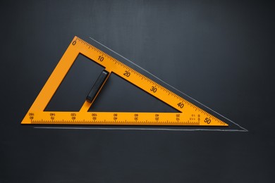 Triangle ruler with drawn acute angle on blackboard, top view