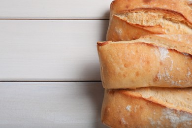 Photo of Tasty baguettes on white wooden table, flat lay. Space for text