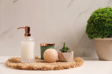 Photo of Soap dispenser, plants and burning candle on countertop in bathroom