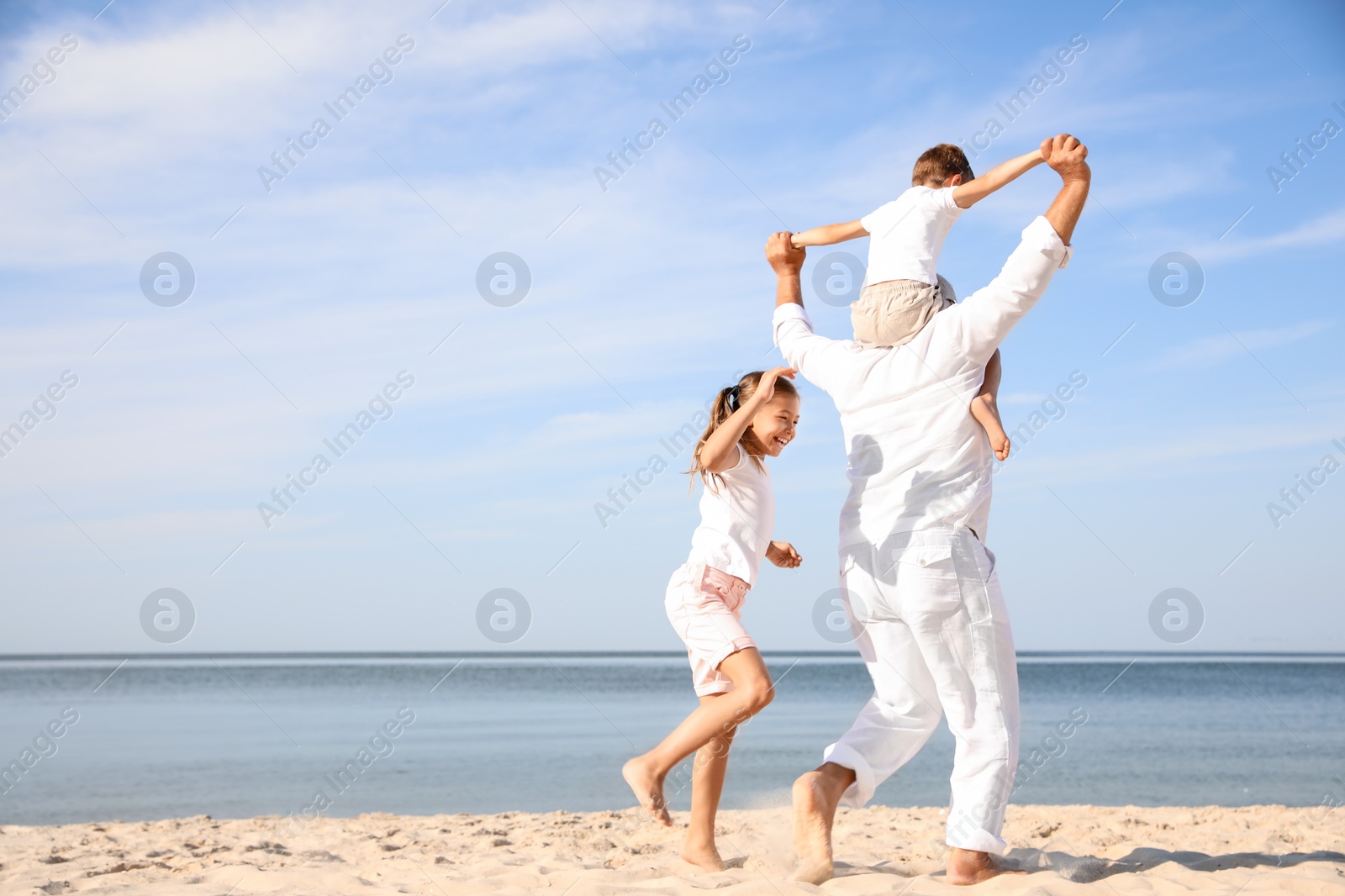 Photo of Cute little children with grandfather spending time together on sea beach